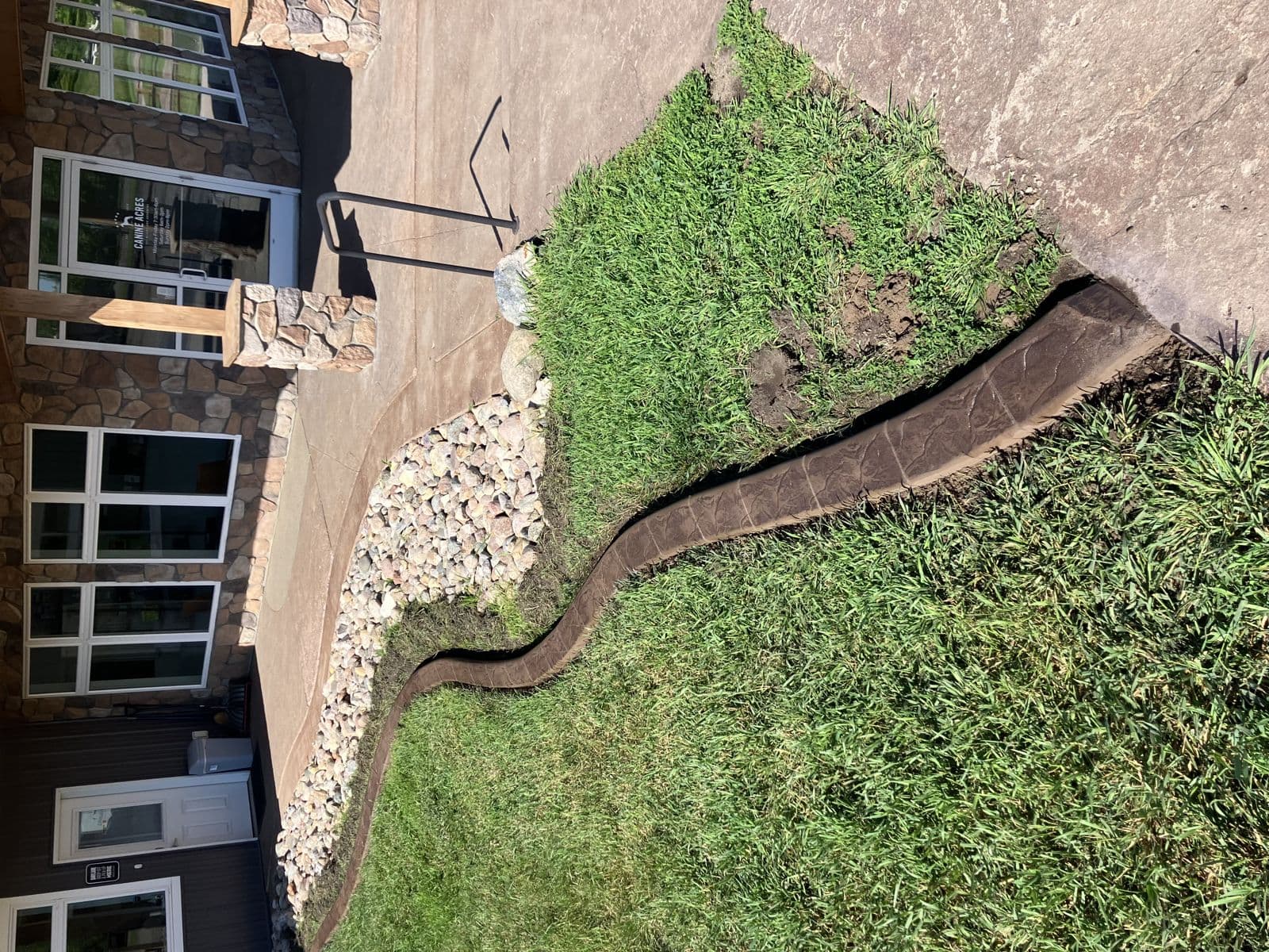 Walnut stamped curbing around a rock landscape bed at Canine Acres
